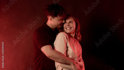 Young couple embracing, showing happiness and connection under romantic red light