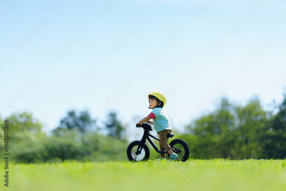 Obraz premium キックバイクで公園を走る2歳の男の子