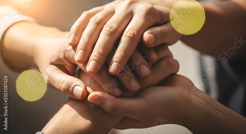Hands together in support with sunny bokeh effect, teamwork closeup