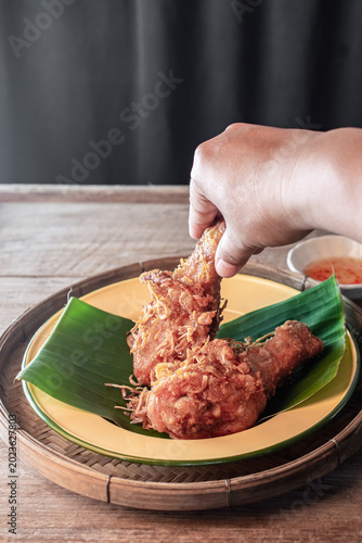 Cuadro en lienzo Authentic Hat Yai fried chicken drumsticks topped with crispy fried shallots served on a green banana leaf in a wooden tray