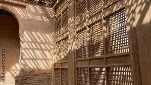 Sunlight patterns on ancient wooden lattice and textured wall in historic building