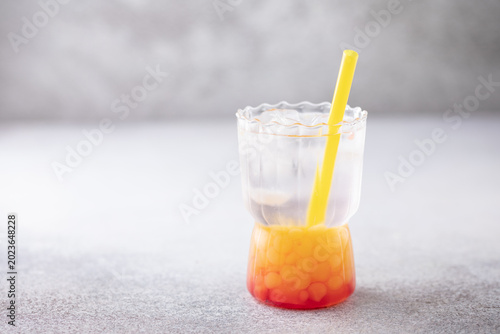 Glass of homemade fruit lemonade with popping boba or bubble pearls. Trendy summer drink