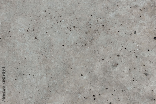Gray concrete surface with scattered pits and pockmarks as a rough grunge background