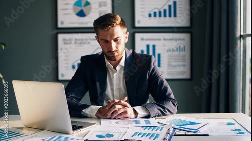 A businessman analyzing data on his laptop in a modern office video