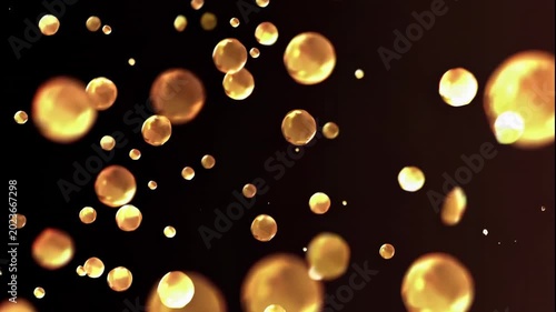 A mesmerizing video of glowing golden bubbles floating in the dark