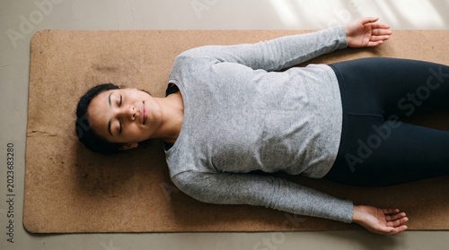 Woman lying on yoga mat in relaxed meditation pose for wellness