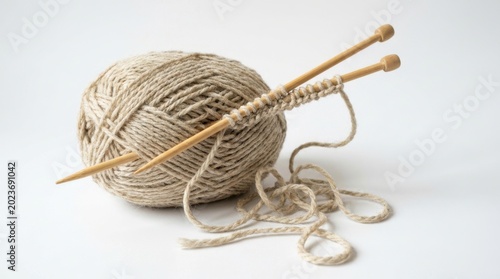 Natural beige yarn ball with wooden knitting needles on clean for crafting isolated on white background