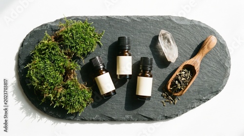 Flat lay of organic essential oil bottles on a slate board with moss.