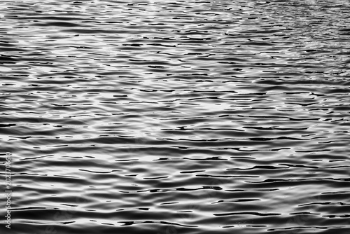 Photos High-contrast black and white abstract of water ripples, creating a rhythmic pattern of light and shadow