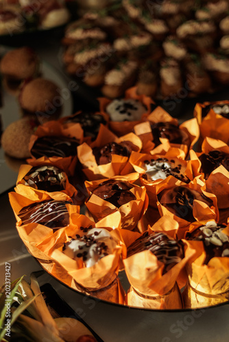 Canvas-taulu Chocolate and vanilla muffins decorated with chips and icing are arranged for a catered event