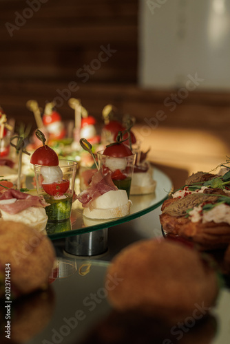 Foto Gourmet appetizers featuring cherry tomatoes, mozzarella, and cured meat are displayed on a reflective surface