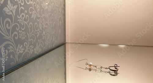 Silver earrings on reflective surface closeup.