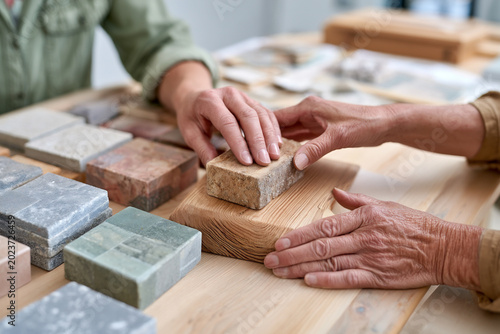 Close-up of designer hands selecting stone and wood samples for garden design.