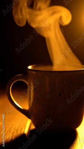 Warm cup of tea steaming on dark wooden table