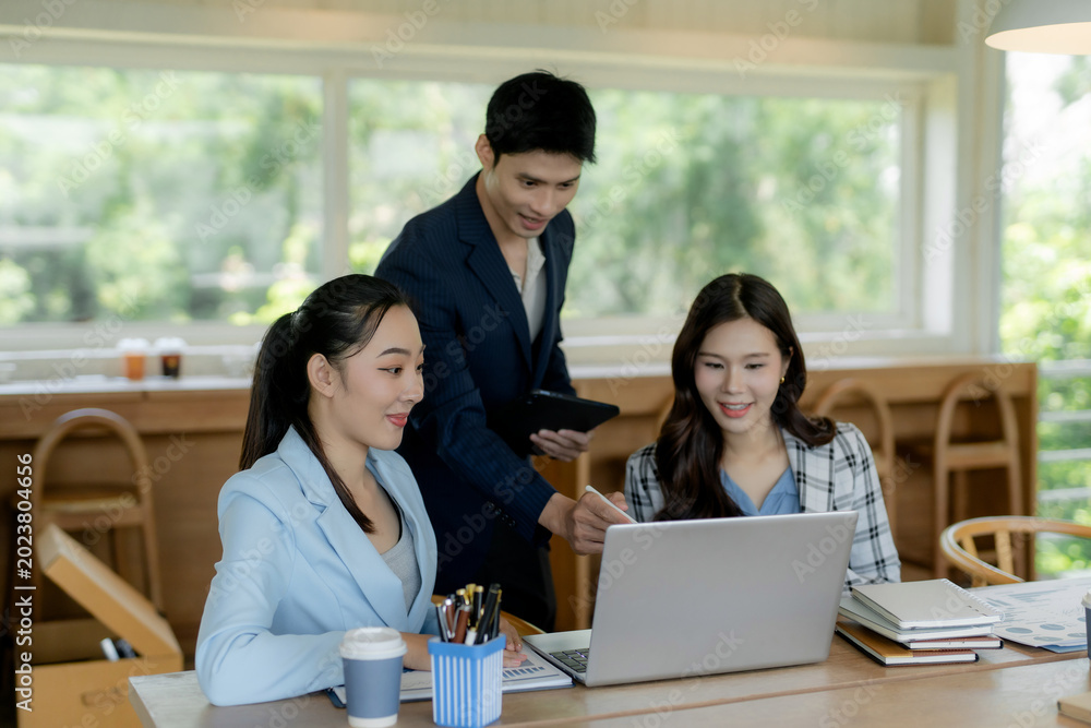 Obraz premium Asian business team collaborating, discussing ideas, and working together on a laptop in a contemporary office environment