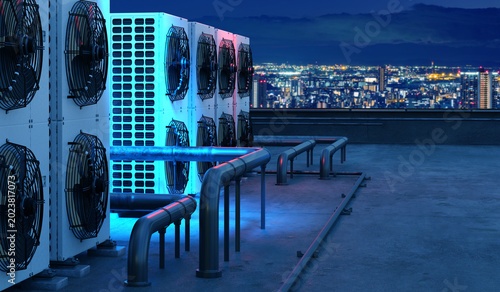 HVAC service maintains rooftop air conditioning units and pipework above city buildings for commercial cooling and ventilation systems