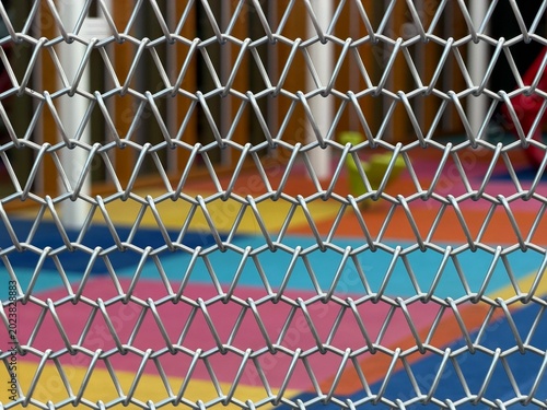 Shiny Metal Wire Grid Pattern with Colorful Playground Backdrop