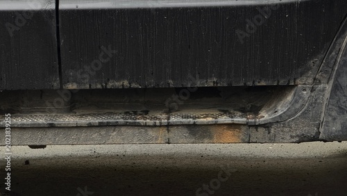 Photos Detailed view of a dirty car rocker panel covered in mud, rust spots, and dirt, indicating lack of maintenance