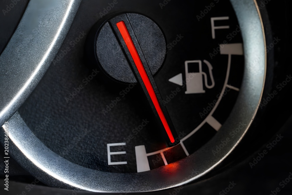 Naklejka premium Low fuel gauge on car dashboard, close-up.