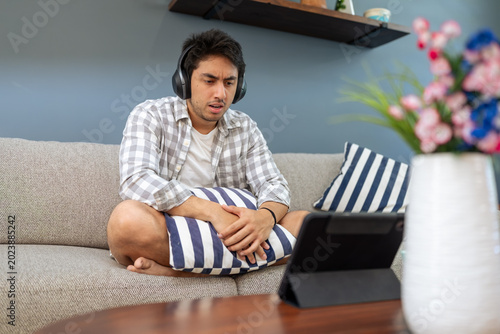 Φωτογραφία Young man concentrating on tablet with headphones at home