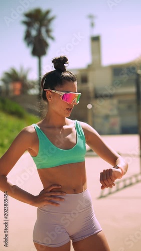 Energetic female jogger taking break on sunlit seaside promenade