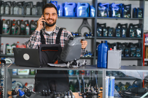 Mechanic talking on phone holding oil in auto parts store