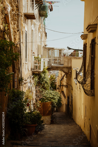 Traditional narrow pedestrian street with hanging laundry and old stone archway in Naples Italy