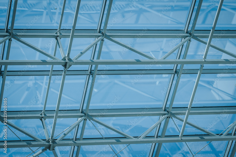 Fototapeta premium Glass ceiling structure with metal framework allowing natural light to filter through, creating a bright and airy atmosphere in a modern architectural setting