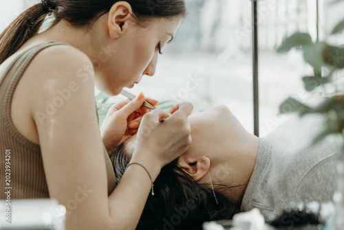 Portrait of a girl cosmetologist extending eyelashes to a woman.