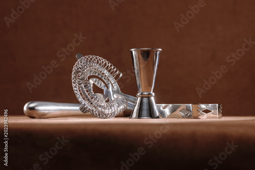 Stainless steel common bar tools including a strainer, a jigger, and ice tongs