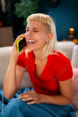 Tableau sur toile A woman sits on a couch at home, holding a phone to her ear
