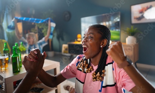 Fotografie Group of friends enjoy a sports game in a living room