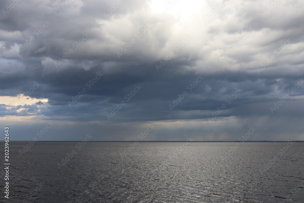 Fototapeta premium Dark storm clouds over calm water before rain