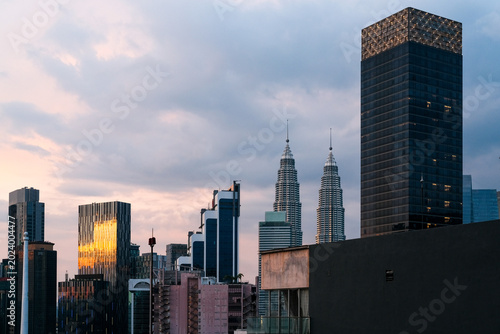 Photography Urban skyline of Kuala Lumpur featuring the iconic Twin Towers standing prominently among modern skyscrapers during blue hour, capturing vibrant city atmosphere and architectural elegance