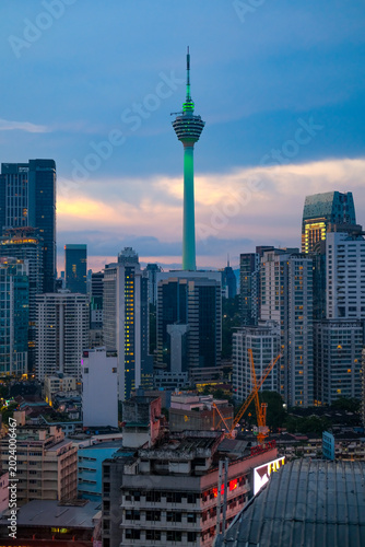 Bukit Bintang cityscape in Kuala Lumpur featuring the majestic Kuala Lumpur Tower surrounded by dense modern buildings, capturing vibrant urban atmosphere during evening hours.