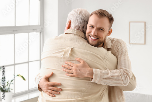 Senior man and his son hugg...