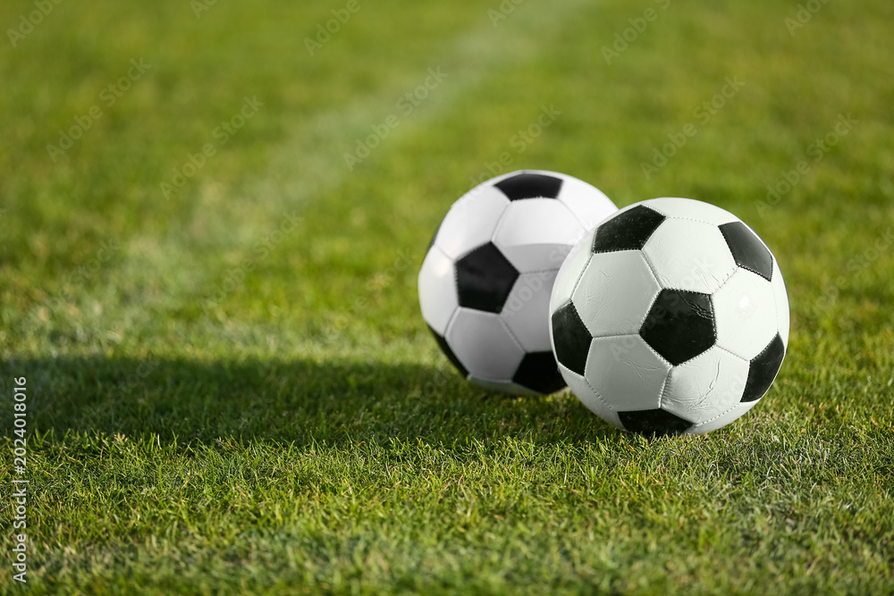 Fototapeta premium Soccer balls on green stadium grass, closeup