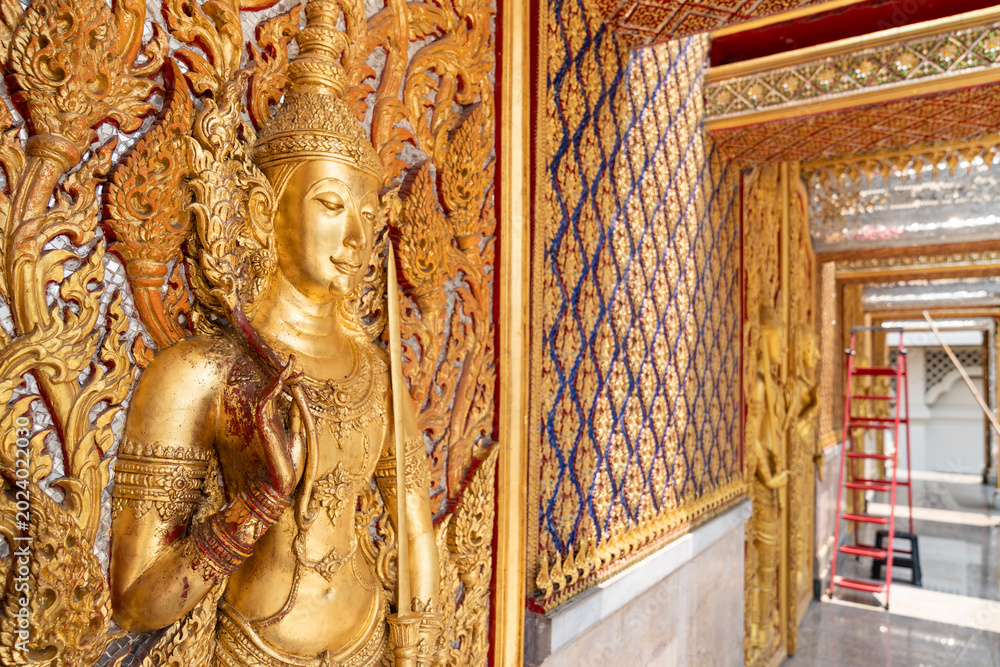 Fototapeta premium High relief guardian figure temple door Prasat Thong Kham Kanchanaphisek golden palace Wat Chantharam, ThaSung UthaiThani Thailand gilded ornament mirrored mosaic.