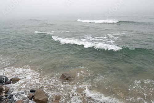 Waves crashing onto the shore on a foggy day