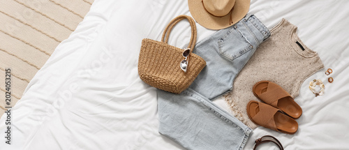 Konstfotografi Stylish blue jeans with top, wicker bag and accessories on bed in room, top view