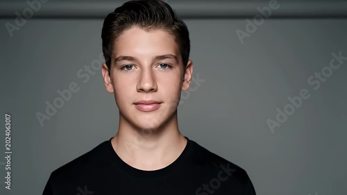Young Man With Blue Eyes And Black T Shirt Posed Against A Gray Background With Studio Lighting