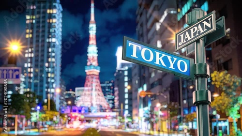Japan city night timelapse with Tokyo Tower and busy traffic. Selective focus of travel sign Tokyo and Japan with real timelapse from raw photos. Busy street and zebra crossing with busy traffic.