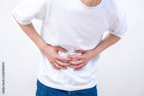 Foto 腹痛でお腹を押さえる男性