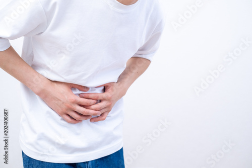Foto 腹痛でお腹を押さえる男性