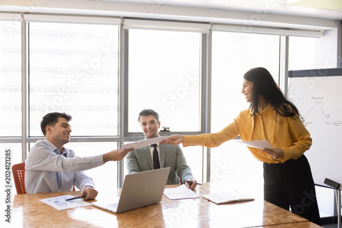 Photography Smiling businesswoman handing out documents to clients or colleagues, sharing ma