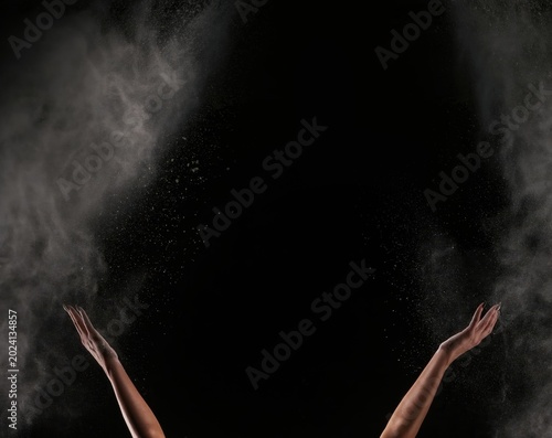 Raised hands throwing white powder into the air