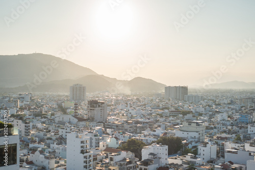 Konstfotografi Panoramic view of Vietnamese city with white buildings stretching to mountains in morning haze