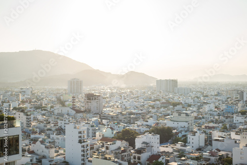 Konstfotografi Panoramic view of Vietnamese city with white buildings stretching to mountains in morning haze