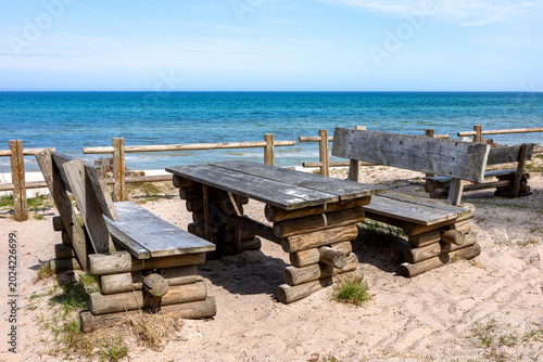 Billede på lærred Wooden benches on the sand above a high bank