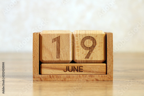 Wooden Block Calendar Showing June 19 on Desk Close Up Date and Time Management Concept